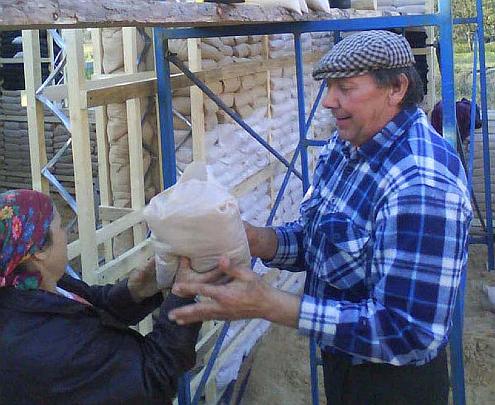 05 sandbag house4.jpg - Workers install sand bags in the post and beam-like construction of Vastu buildings in the Ukraine. Sand is a superior thermal insulator?more efficient than earthen walls and conventional materials?which reduces the cost of maintaining a comfortable temperature year-round.